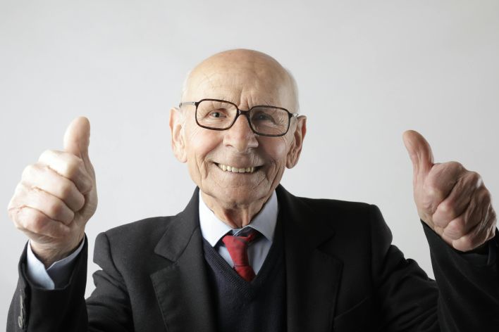 Positive senior man in eyeglasses showing thumbs up and looking at camera