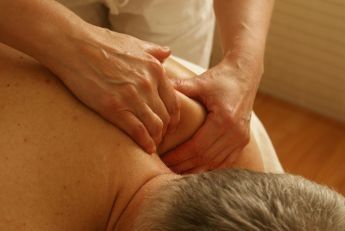 Topless Woman Lying on Bed Getting Massage